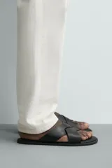 Sandalia plana de cuero negro con dos tiras anchas cruzadas en el empeine y plantilla anatómica.