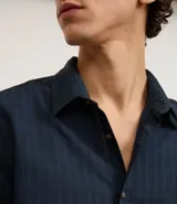 Camisa de manga larga color verde militar, confeccionada en algodón con textura maquinetada, cuello inglés y abotonado delantero. Corte comfort.