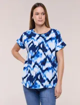 Blusa de silueta holgada y recta, confeccionada en crepe de poliéster con estampado animal print. Presenta escote redondo clásico, mangas cortas de hombro caído con puño doblado y ruedo ligeramente curvo.