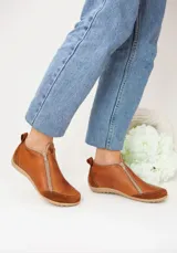 Zapatito marrón de cuero con puntera de gamuza, cierre frontal con cremallera y tirador trasero.