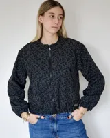 Campera bomber negra con diseño estampado de monogramas, cierre frontal y puños elásticos.