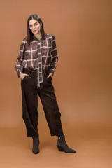 Camisa de manga larga con estampado de cuadros escoceses en tonos marrones y blancos, cuello clásico con lazo integrado y cierre frontal abotonado.