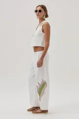 Chaleco blanco de gabardina con bordados florales y cierre frontal con botones forrados en la misma tela.