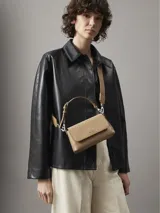 Cartera bandolera Calvin Klein color beige con monograma en relieve. Tiene correa ajustable, cierre de cremallera y logo de la marca en el frente.