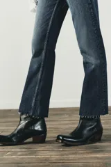 Jeans de tiro alto color marrón oscuro con acabado lavado, corte recto/flare y bajo cropped sin costuras. Presenta cinco bolsillos y cierre frontal con cremallera y botón metálico.