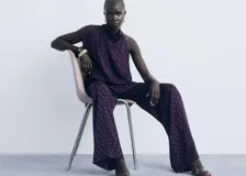 Blusa sin mangas de corte recto con cuello drapeado y cierre de botones. Presenta un diseño estampado de lunares en color azul sobre fondo oscuro.