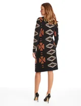 Vestido de punto con diseño integrado que simula un conjunto de vestido negro liso con un cárdigan largo estampado con patrón geométrico de eslabones. Presenta escote redondo y mangas largas.