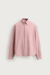 Camisa de corte relaxed fit confeccionada en tejido de algodón con diseño de rayas verticales en tonos rosados y blancos. Cuenta con cuello abotonado, manga larga con puños abotonados y bajo asimétrico.