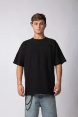 Remera negra de corte oversize con cuello redondo y mangas cortas. Presenta la palabra "simplify" bordada en el pecho en el mismo tono. Confeccionada en tejido de punto con textura sutil tipo waffle.