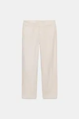 Pantalón de mujer color beige claro, tiro medio, con corte recto y ancho, confeccionado en algodón. Presenta bolsillos delanteros y bolsillos de vivo en la espalda, cintura con trabillas y cierre frontal con cremallera y gancho metálico.
