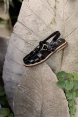 Sandalias de cuero con tiras entrecruzadas, suela plana y hebilla lateral.