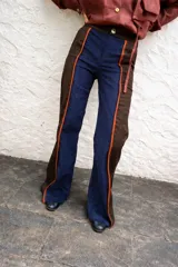 Pantalón de paño con silueta recta levemente acampanada, cierre frontal y bolsillos laterales. Presenta recortes combinados en color azul marino y marrón con detalles de tiras en cuero.