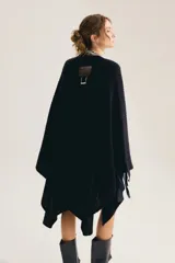 Poncho de punto grueso y sin mangas, color marrón tostado, abierto como capa y con ruedo asimétrico.