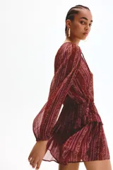 Vestido corto de manga larga confeccionado en tejido transparente, con estampado estilo paisley en tonos borravino y rosado. Presenta cuello redondo con abertura frontal y cordones para atar, cintura elástica y falda con volados en capas.