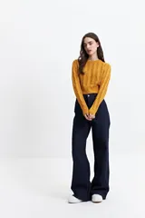 Sweater de punto color mostaza, con diseño de ochos y textura calada. Tiene cuello redondo, mangas largas y terminaciones acanaladas en puños y cintura.