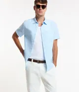 Camisa de manga corta confeccionada en mezcla de lino y algodón, con cuello inglés, cierre frontal de botones y bolsillo en el pecho. Presenta un corte comfort holgado y diseño liso.
