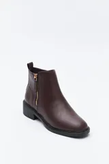 Bota corta de cuero sintético color negro, con taco bajo cuadrado y cierre lateral metálico. Presenta un detalle texturizado tipo reptil en la parte posterior del talón.