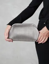 Cartera tipo clutch de mano con diseño estructurado y silueta redondeada. Presenta un acabado plateado metalizado con textura de plisado tubular vertical y cierre de marco rígido.