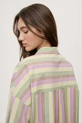 Camisa oversize de manga larga con estampado de rayas verticales en tonos rosado, celeste y verde menta. Cuenta con cuello camisero, cierre frontal con botones y un bolsillo aplicado en el pecho.