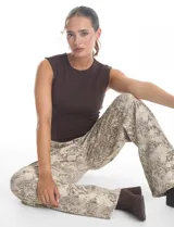 Jean de corte wide leg con estampado animal print de serpiente en tonos beige y gris. Presenta diseño clásico de cinco bolsillos, presillas para cinturón y cierre frontal con botón metálico.