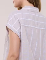Camisa de lino de estructura recta, color beige con rayas verticales blancas. Cuenta con cuello solapa, escote en V abierto, abotonadura frontal, bolsillo plaqué en el pecho, mangas cortas de hombro caído y ruedo recto.
