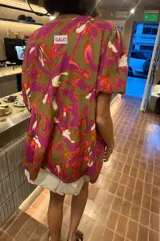 Blusa de calce holgado con estampado floral en tonos marrones, fucsias, naranjas y blancos. Tiene escote en V con doble lazo ajustable y mangas 3/4 con volumen.