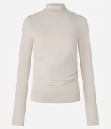 Blusa color beige de poliéster con cuello alto, mangas largas y fruncidos delanteros.