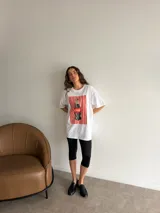 Remerón de algodón blanco con corte oversize y cuello redondo, que presenta un estampado frontal con diseño de una lata de sardinas sobre fondo de rayas.
