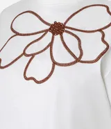 Blusa boxy de mangas cortas color blanco, confeccionada en algodón, con cuello redondo y bordado floral en el frente.