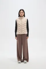 Chaleco acolchado de diseño capitoneado con cierre frontal y bolsillos laterales. Presenta un cuello alto y detalles de botones metálicos decorativos.