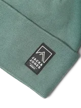 Gorro de punto color verde oliva, con diseño de tejido acanalado y parche rectangular con logo en el frente.