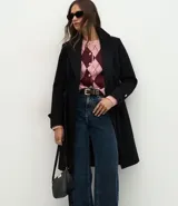 Saco femenino de corte midi confeccionado en polyvelour, con diseño cruzado, cuello tipo blazer, mangas largas con detalles en puños, cierre frontal con lazo ajustable en la cintura y botones metalizados decorativos.