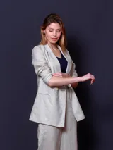Blazer de lino color beige claro, de corte recto y manga larga. Presenta solapas de muesca, cierre frontal de un solo botón y bolsillos de parche.