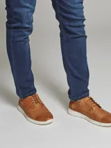 Zapato acordonado de cuero color marrón con suela blanca de PVC.