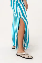 Falda larga tejida a rayas verticales turquesas y blancas, con pretina elástica y tajos laterales.