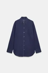 Camisa de corte amplio confeccionada en algodón, con cuello solapa, manga larga, bolsillo delantero de plastrón y cierre frontal con botones.