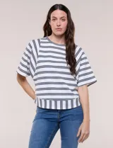 Remera de corte holgado color blanco con rayas horizontales oscuras, escote redondo a la base y mangas cortas amplias tipo murciélago. Presenta una banda ancha en el ruedo inferior con rayas verticales.