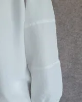 Blusa de mangas tres cuartos con diseño de corte recto y cuello redondo. Presenta costuras horizontales decorativas en las mangas y un acabado liso.