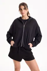 Campera deportiva negra de corte bomber sin friza, con cierre frontal completo, capucha y elásticos ajustables en la cintura.