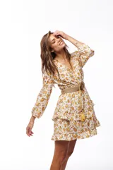 Vestido corto con estampado floral amarillo y blanco, mangas largas abullonadas y falda con volados. Incluye cinturón de soga.