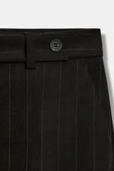 Pantalón de tiro medio con diseño de raya diplomática, confeccionado con cintura con trabillas, bolsillos laterales y cierre frontal con cremallera y botón.
