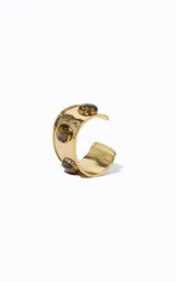 Brazalete rígido de metal dorado de banda ancha, con abertura frontal y piedras redondeadas con efecto veteado incrustadas.