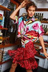 Falda corta tipo pareo con estampado abstracto multicolor y flecos de seda rojos en el ruedo.