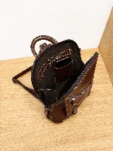 Mochila de cuero vacuno color marrón, con diseño estructurado y combinación de textura croco en el bolsillo frontal. Cuenta con un compartimento principal con cierre, un bolsillo frontal con cierre metálico y hebillas decorativas, y correas regulables.