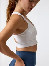 Top deportivo blanco con cortes y pespuntes inspirados en la época victoriana, que aportan un diseño de estética corsetera y ofrecen alta sujeción.