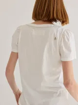 Remera de algodón con escote en V, mangas cortas con frunces en los hombros y detalle de bolsillo frontal con costuras a la vista.