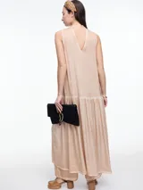 Vestido largo de viscosa en color beige con efecto gastado, diseño sin mangas con escote halter y tira tipo choker para anudar al cuello. Presenta un corte a la altura de la cadera con falda fruncida que aporta volumen y movimiento.