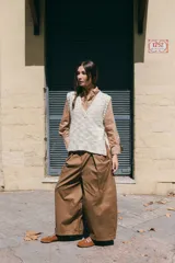 Chaleco tejido de lana rústica en color crudo, con cuello en V y aberturas laterales ajustables con lazos.