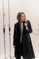 Tapado largo de corte recto y estilo minimalista, confeccionado en tela de color negro. Presenta solapas amplias, bolsillos frontales de parche y un diseño abierto que permite superponer capas.