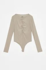 Body negro de microfibra translúcida esmerilada, ajustado al cuerpo, con mangas largas, cuello media polera y frunce central en el delantero. Tiene acceso por entrepierna con broches metálicos.